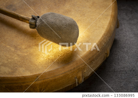 backlit, handmade, native American style, shaman frame drum covered by goat skin with a beater 133086995
