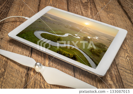 sunrise over a river meandering through Nebraska Sandhills - reviewing aerial image of Middle Loup RIver on a digital tablet 133087015