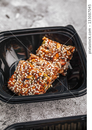 Sesame nut brittle pieces in container Sesame nut brittle pieces in container 133087045