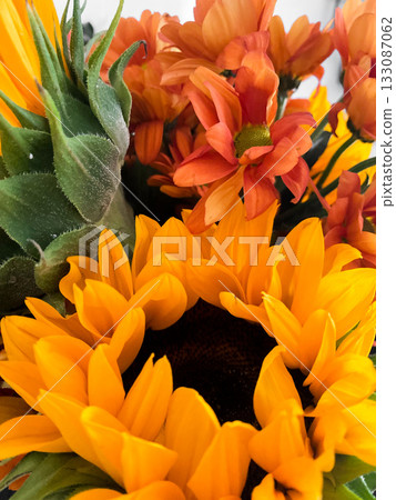 Beautiful floral bouquet with vibrant sunflowers mixed with orange and yellow flowers. Sunflowers with bold petals, smaller blooms add pop of color. Lively display perfect for decor or celebrations Beautiful floral bouquet with vibrant sunflowers mixed with orange and yellow flowers. Sunflowers with bold petals, smaller blooms add pop of color. Lively display perfect for decor or celebrations 133087062