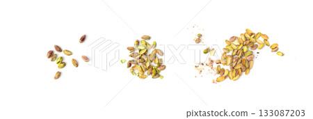Fried salt pistachio nuts pieces pile isolated. Baked broken pistachios grains, crumbled green pistache 133087203