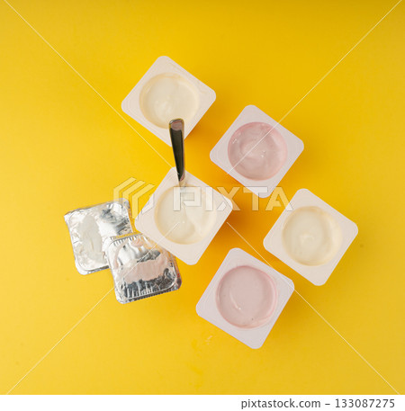 Yogurt cups set, pink and yellow fruit yoghurt in plastic pots, milk pudding container with spoon Yogurt cups set, pink and yellow fruit yoghurt in plastic pots, milk pudding container with spoon 133087275