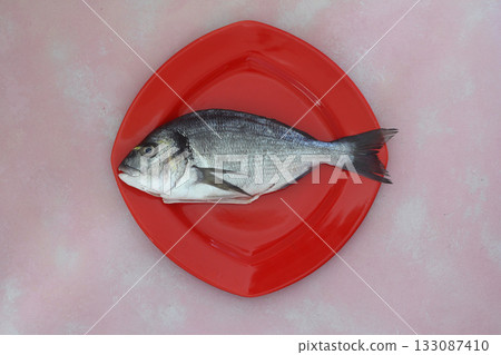 fresh fish on a pink wooden board. Raw uncooked sea bream on red plate. 133087410