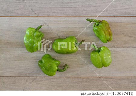 Organic green pepper in wooden plate on dark wooden table background, top view, copy space Organic green pepper in wooden plate on dark wooden table background, top view, copy space 133087418