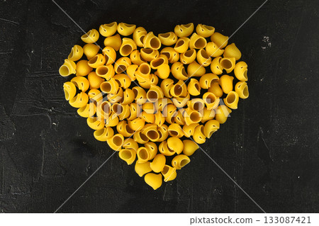 Pasta in the shape of a heart on a black background. 133087421
