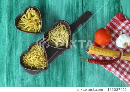 Italian Food background on green table Top view. With heart shaped bowl 133087431