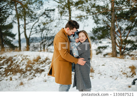 happy young family of three in the park on a snowy winter day happy young family of three in the park on a snowy winter day 133087521