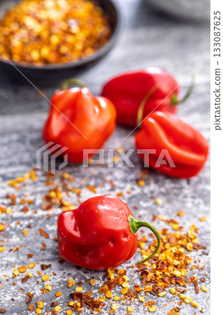 Red chili pepper habanero and chili flakes on kitchen table. Red chili pepper habanero and chili flakes on kitchen table. 133087625