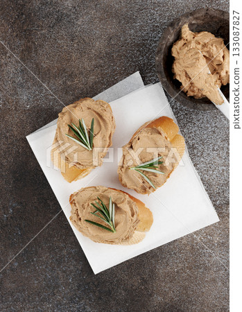 Toasted baguette slices with homemade chicken liver pate and rosemary on gray background. 133087827