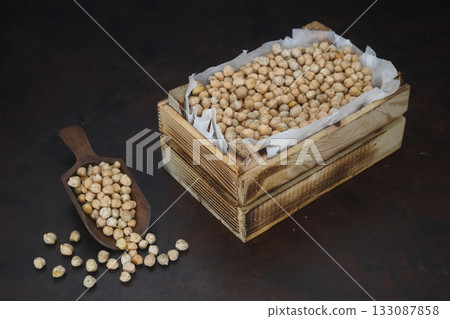 chickpeas in a small wooden crate, isolated on black background. With Wooden Spoon. 133087858