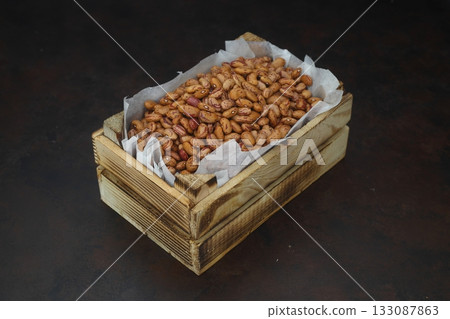 Kidney beans in a small wooden crate, isolated on black background. With wooden spoon. 133087863