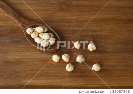 Dry chickpeas in a wooden spoon close-up on a wooden background. Vegetarian food. Dry chickpeas in a wooden spoon close-up on a wooden background. Vegetarian food. 133087868