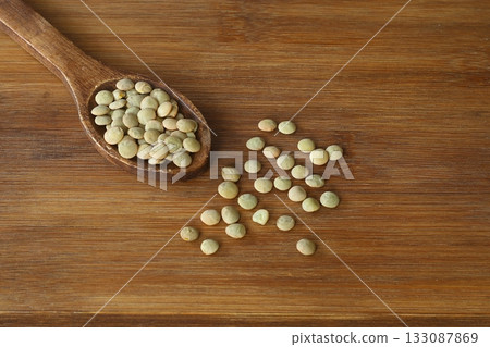 Green Lentils in a wooden spoon close-up on a wooden background. Vegetarian food. 133087869