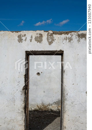 Ruins of an old concrete structure with a door frame under blue sky 133087940