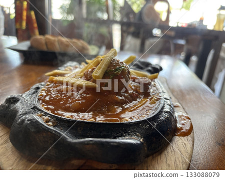 Sizzling Vietnamese Bo Ne with beef, a fried egg, and fries on a hot cast iron platter Sizzling Vietnamese Bo Ne with beef, a fried egg, and fries on a hot cast iron platter 133088079