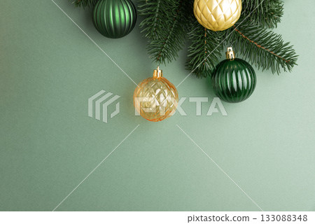 Green and Gold Christmas Ornaments Hanging on Pine Branches over Muted Green Background Green and Gold Christmas Ornaments Hanging on Pine Branches over Muted Green Background 133088348