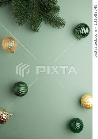 Fir Tree Branch with Green and Golden Christmas Ornaments on Green Background in Festive Flat Lay 133088349