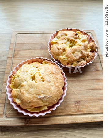 Homemade apple cakes in silicone molds on wooden board. Pastry preparation, sweet baking, and simple dessert recipe at home. Homemade apple cakes in silicone molds on wooden board. Pastry preparation, sweet baking, and simple dessert recipe at home. 133088386
