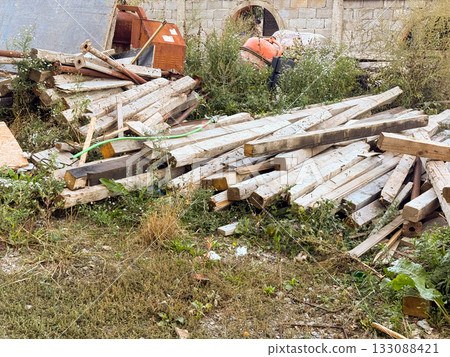 Weathered planks and tools in messy backyard. Construction process, urban decay, and environmental impact of waste materials. 133088421