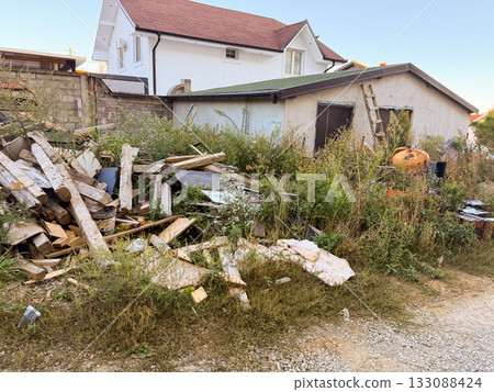 Construction waste near unfinished house. Abandonment, decay, and rural environment captured in suburban neighborhood. Construction waste near unfinished house. Abandonment, decay, and rural environment captured in suburban neighborhood. 133088424