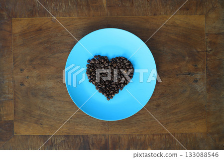 Roasted coffee beans in heart shaped bowl on dark background. Love coffee concept. Top view flat lay with copy space Roasted coffee beans in heart shaped bowl on dark background. Love coffee concept. Top view flat lay with copy space 133088546