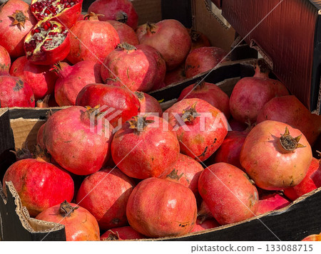 Fresh pomegranates displayed in boxes at street market. Organic fruit, local agriculture, and vibrant color of seasonal harvest. 133088715