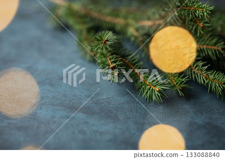 Fir branches and Christmas lights with a bokeh effect on a dark blue background Fir branches and Christmas lights with a bokeh effect on a dark blue background 133088840