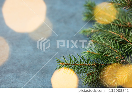Fir branches and Christmas lights with a bokeh effect on a dark blue background Fir branches and Christmas lights with a bokeh effect on a dark blue background 133088841