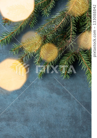 Fir branches and Christmas lights with a bokeh effect on a dark blue background Fir branches and Christmas lights with a bokeh effect on a dark blue background 133088842