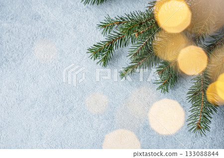 Fir branches and Christmas lights with a bokeh effect on a light blue background Fir branches and Christmas lights with a bokeh effect on a light blue background 133088844