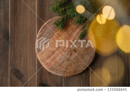 Fir branches and Christmas lights with a bokeh effect on a dark wooden background Fir branches and Christmas lights with a bokeh effect on a dark wooden background 133088845