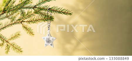 Fir tree branches with a Christmas tree ornament with a bokeh effect from the garland 133088849