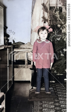 Vintage portrait of a cute little girl by the Christmas tree. Retro photo from 1972. Vintage portrait of a cute little girl by the Christmas tree. Retro photo from 1972. 133089016