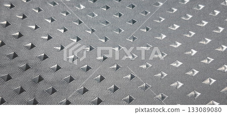 Metallic grey textured surface with raised diamond studs. Textured metallic grey surface featuring a pattern of raised diamond studs. Metallic grey textured surface with raised diamond studs. Textured metallic grey surface featuring a pattern of raised diamond studs. 133089080