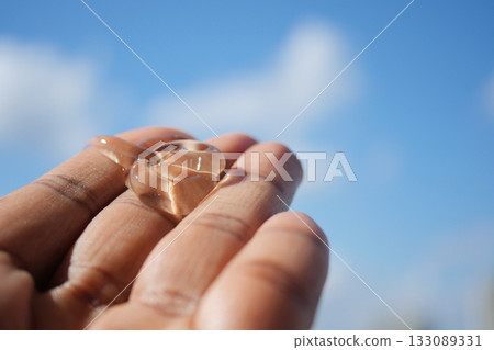 Hand holding aloe vera gel against blue sky Hand holding aloe vera gel against blue sky 133089331