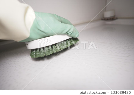 Cleaning a toilet surface with a green brush in a bright space Cleaning a toilet surface with a green brush in a bright space 133089420