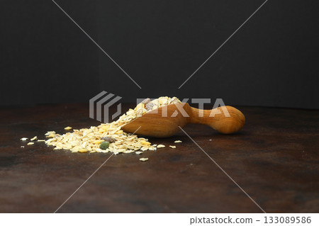 Healthy cereal breakfast. Mixed muesli in wooden scoop isolated on rusty background Healthy cereal breakfast. Mixed muesli in wooden scoop isolated on rusty background 133089586