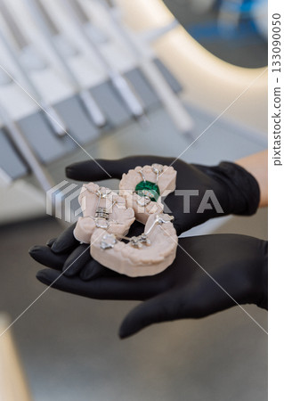 Orthodontic palatal expander models in gloved hands at dental clinic, closeup 133090050