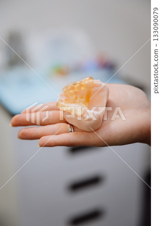 Transparent implant surgical guide on dental jaw model in clinician hand, clinic closeup Transparent implant surgical guide on dental jaw model in clinician hand, clinic closeup 133090079