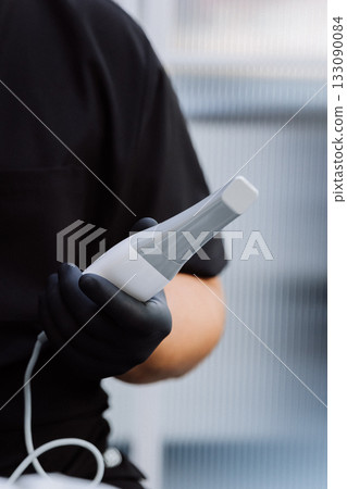 Intraoral dental scanner in gloved hand, modern digital dentistry closeup 133090084
