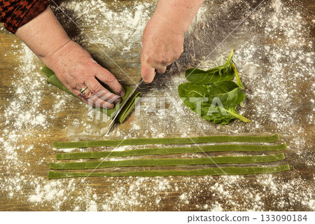 Hands cutting purple noodles with ingredients on the table, homemade italian food. Hands cutting purple noodles with ingredients on the table, homemade italian food. 133090184