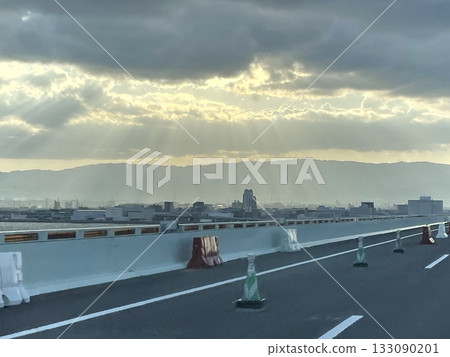 從關西國際機場連接橋上望去,晨光透過厚厚的雲層縫隙灑下,遠處群山巍峨。 從關西國際機場連接橋上望去,晨光透過厚厚的雲層縫隙灑下,遠處群山巍峨。 133090201