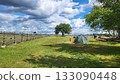 Camping site with a tent and open field under a partly cloudy sky near a wooden fence in the countryside 133090448
