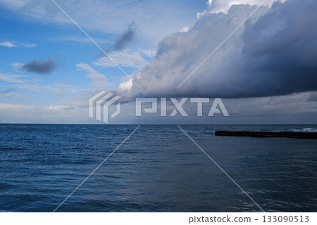 Dramatic ocean view with approaching storm clouds. Expansive sea view under a sky filled with thick, dark storm clouds approaching from the right.  133090513