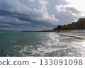 Dramatic coastal view under dark clouds. The turbulent waves of the Black Sea crash onto the sandy beach of Odessa under a sky full of dark, dramatic clouds. 133091098