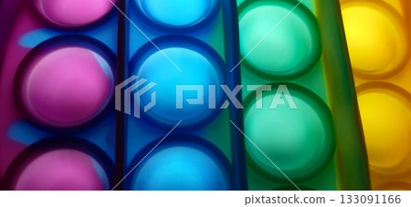 Vibrant rainbow pop it fidget toy close-up. Close-up of a multicolored pop it fidget toy, featuring rows of bubble-like protrusions in vibrant colors: red, orange, yellow, green, blue, and purple. Vibrant rainbow pop it fidget toy close-up. Close-up of a multicolored pop it fidget toy, featuring rows of bubble-like protrusions in vibrant colors: red, orange, yellow, green, blue, and purple. 133091166