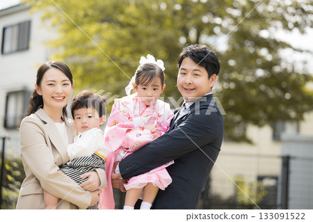 戶外全家福，適合七五三節或週年紀念：一家四口面帶微笑，看向鏡頭。 133091522