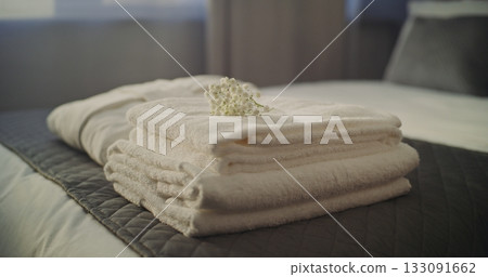 Maids Gloved Hands Arranging Crisp Towels and Soft Bathrobe on Hotel Bed, Finishing With Flower Maids Gloved Hands Arranging Crisp Towels and Soft Bathrobe on Hotel Bed, Finishing With Flower 133091662