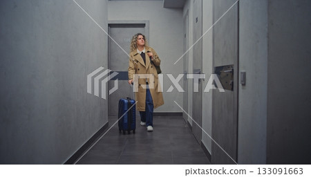 Woman With Suitcase Walks Through Quiet Hotel Corridor, Searching For Room Woman With Suitcase Walks Through Quiet Hotel Corridor, Searching For Room 133091663