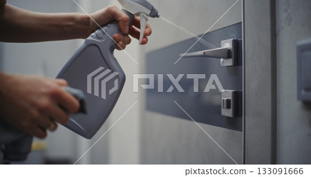 Maid Disinfects Door Handle and Lock Using Cleaning Solution and Microfiber Cloth 133091666